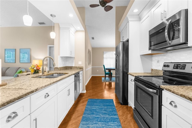 kitchen featuring stainless steel appliances, ceiling fan, decorative backsplash, and wood-type flooring