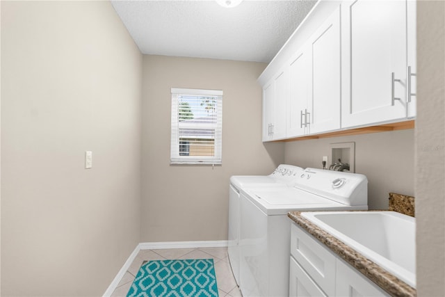 washroom featuring sink, cabinets, washer and clothes dryer, a textured ceiling, and light tile patterned floors