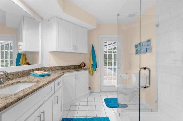 bathroom with tile patterned floors, a shower with door, vanity, and toilet