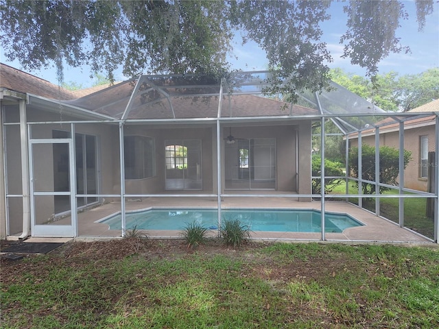 rear view of property featuring glass enclosure and a patio