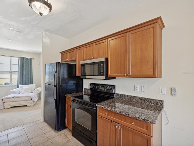 kitchen with black appliances, dark stone countertops, and light tile patterned flooring