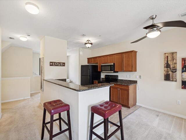 kitchen with light carpet, dark stone countertops, a kitchen breakfast bar, black appliances, and ceiling fan