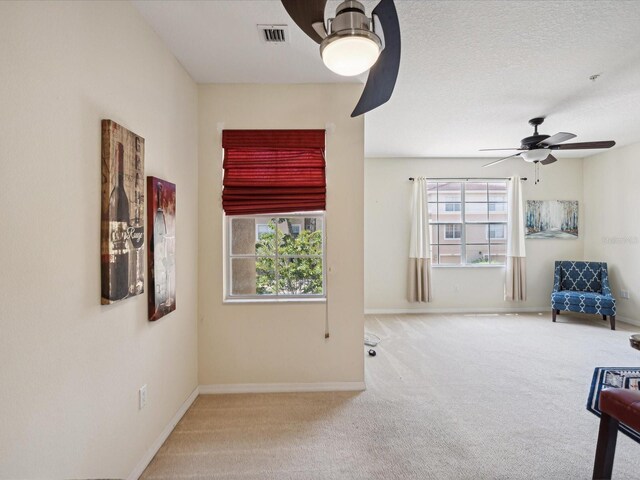 unfurnished room featuring a textured ceiling, ceiling fan, and carpet flooring