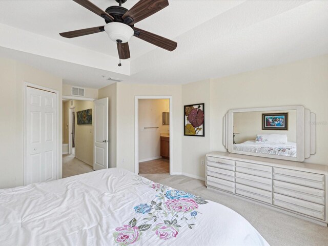 carpeted bedroom featuring connected bathroom, ceiling fan, and a closet