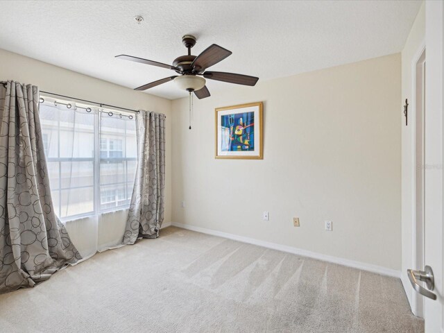 carpeted spare room featuring a textured ceiling and ceiling fan