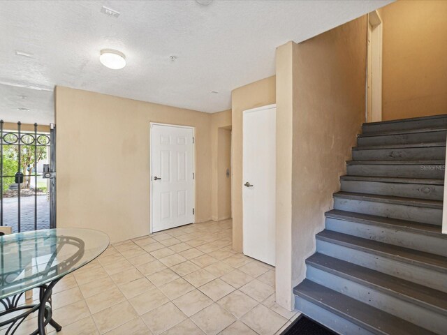 stairway featuring tile patterned flooring and a textured ceiling