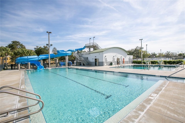 view of swimming pool featuring a water slide and a patio area