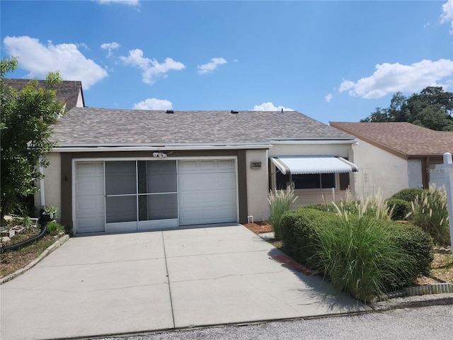 ranch-style home featuring concrete driveway, a shingled roof, an attached garage, and stucco siding