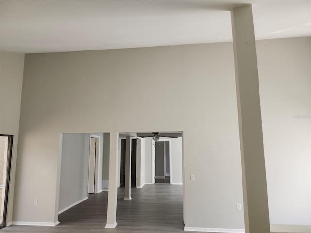 spare room featuring wood finished floors, a towering ceiling, and baseboards