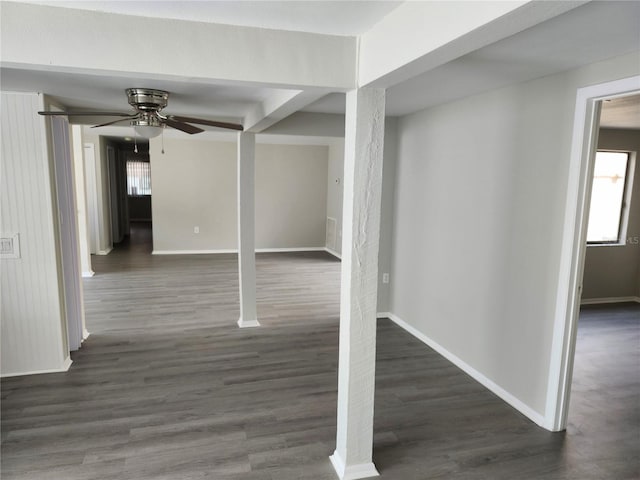 interior space with a ceiling fan, baseboards, and dark wood-style flooring