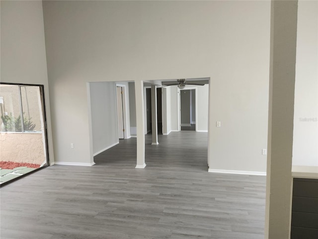 empty room with a high ceiling, baseboards, and wood finished floors