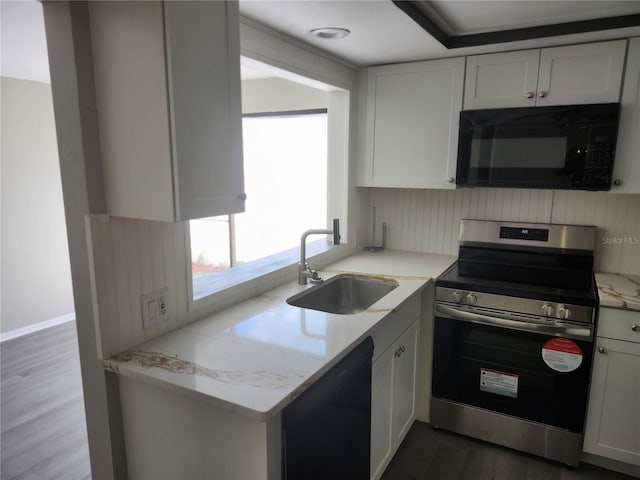 kitchen featuring light stone counters, white cabinets, a sink, wood finished floors, and black appliances