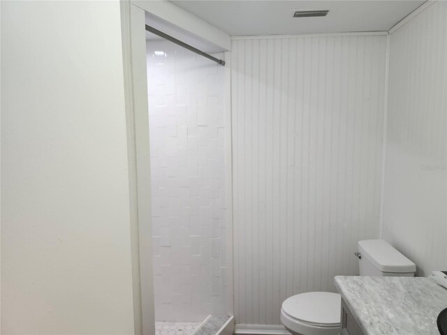 bathroom with toilet, vanity, and tiled shower