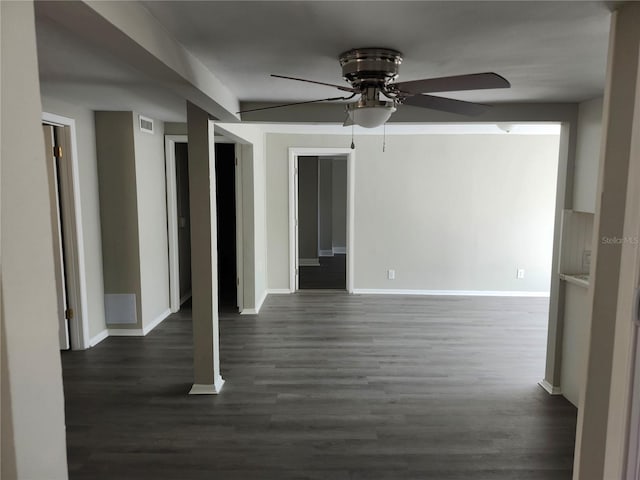 spare room with a ceiling fan, dark wood-style flooring, visible vents, and baseboards