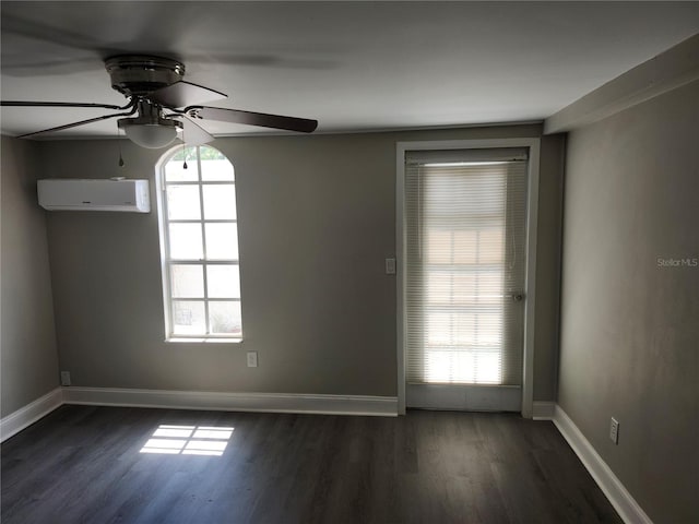 spare room featuring dark hardwood / wood-style flooring, a wall unit AC, and ceiling fan