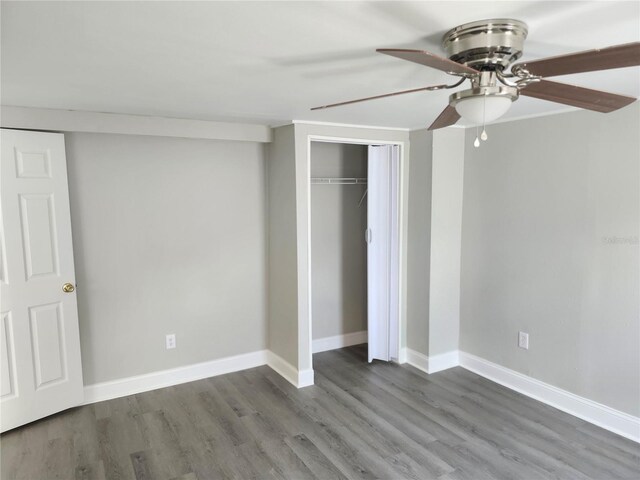 unfurnished bedroom featuring hardwood / wood-style floors, ceiling fan, and a closet