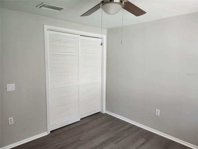 unfurnished bedroom with ceiling fan, a closet, and dark hardwood / wood-style floors