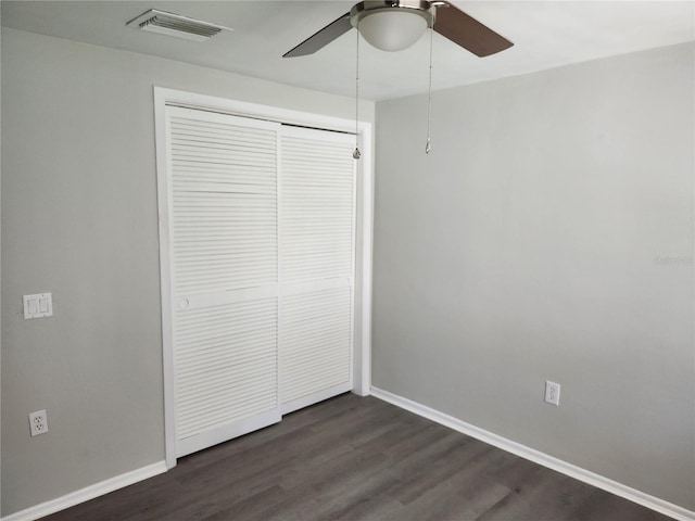 unfurnished bedroom featuring baseboards, visible vents, a ceiling fan, dark wood-style flooring, and a closet