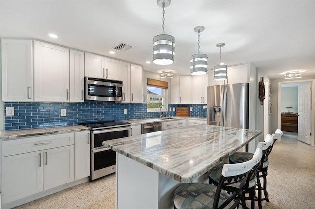 kitchen with white cabinetry, hanging light fixtures, backsplash, and stainless steel appliances