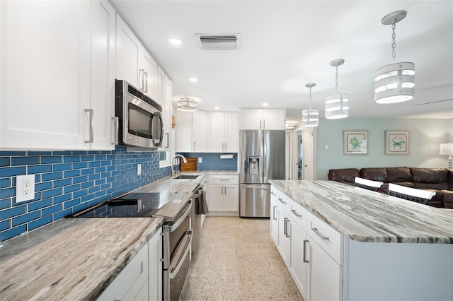 kitchen with white cabinetry, decorative backsplash, hanging light fixtures, and appliances with stainless steel finishes