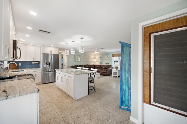 kitchen featuring appliances with stainless steel finishes, a center island, decorative backsplash, and white cabinets