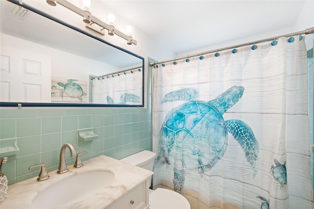 bathroom featuring tile walls, tasteful backsplash, vanity, and toilet