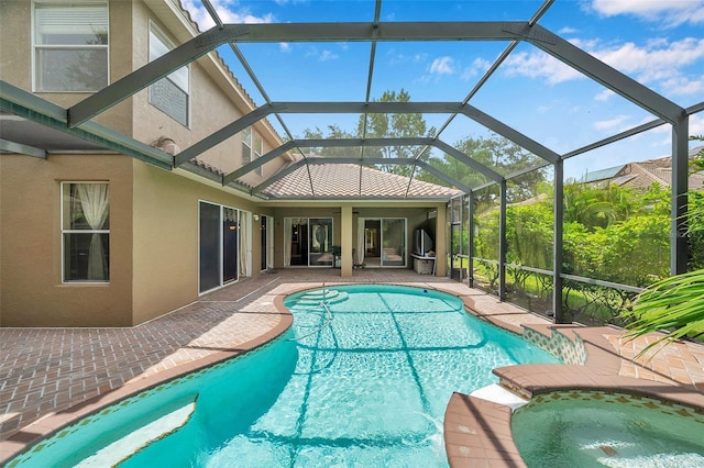 view of swimming pool featuring an in ground hot tub, glass enclosure, and a patio