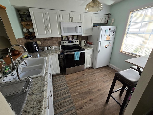 kitchen featuring a wealth of natural light, white appliances, white cabinetry, and hardwood / wood-style flooring