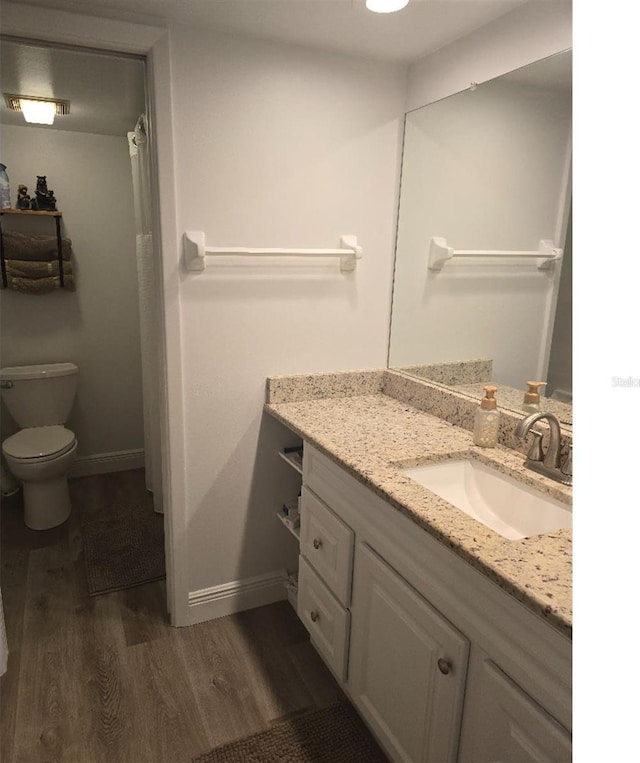 bathroom with vanity, toilet, and hardwood / wood-style floors