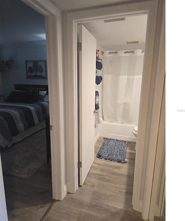 bathroom with hardwood / wood-style floors, toilet, and shower / tub combo with curtain