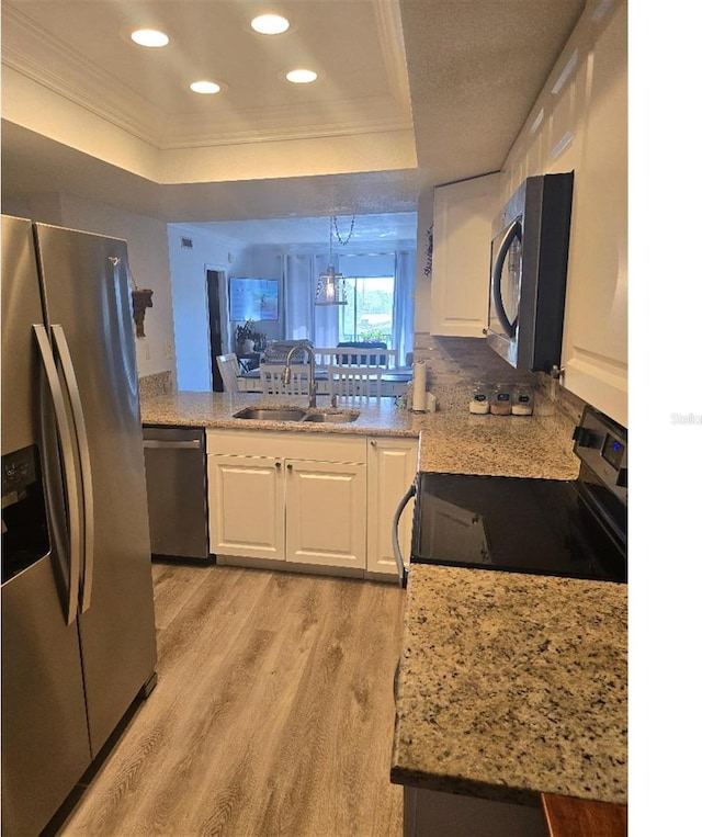 kitchen with appliances with stainless steel finishes, light hardwood / wood-style floors, white cabinetry, and sink