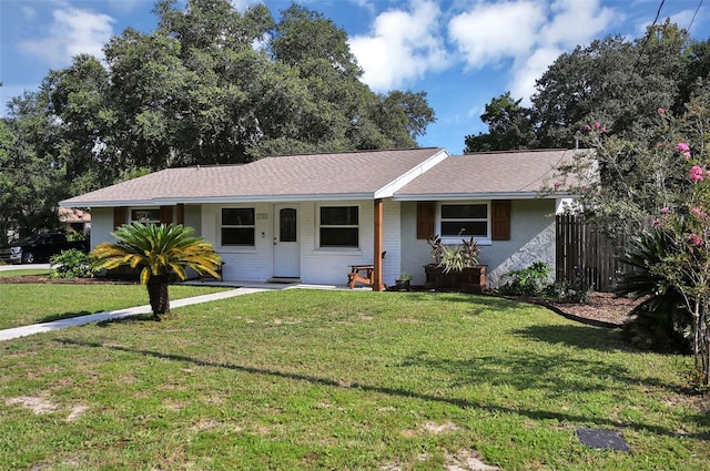 single story home featuring a porch, brick siding, fence, and a front lawn