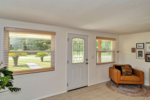 foyer featuring baseboards, a textured ceiling, and light tile patterned flooring