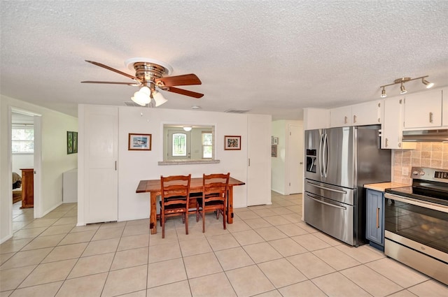 kitchen with stainless steel appliances, light tile patterned flooring, backsplash, and under cabinet range hood