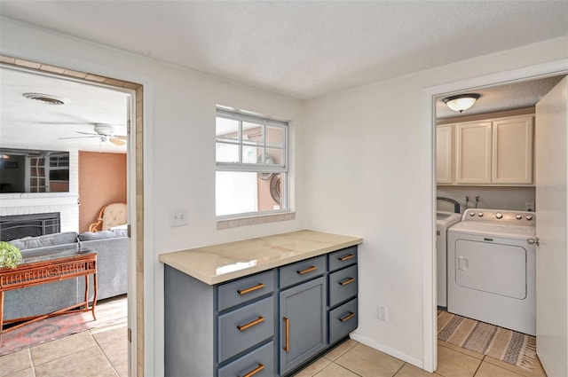 washroom featuring light tile patterned floors, a textured ceiling, separate washer and dryer, a fireplace, and cabinet space