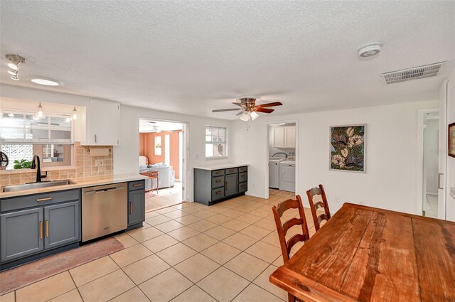 kitchen with washer and clothes dryer, light countertops, visible vents, stainless steel dishwasher, and a sink