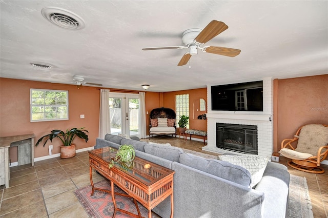 living room with ceiling fan, a fireplace, visible vents, and baseboards