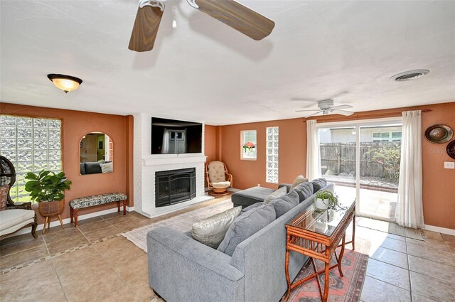 living room featuring ceiling fan, a fireplace, visible vents, and baseboards