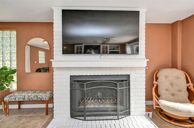 room details with a brick fireplace, baseboards, and a ceiling fan