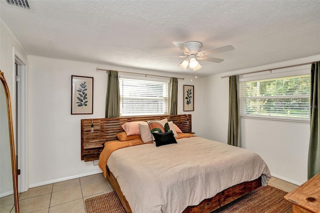 bedroom featuring light tile patterned floors, multiple windows, a textured ceiling, and visible vents