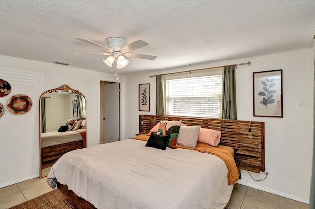 bedroom featuring light tile patterned floors, a textured ceiling, visible vents, and a ceiling fan