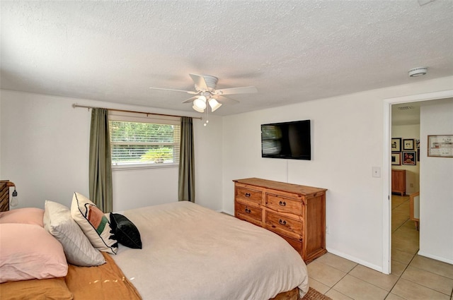 bedroom featuring light tile patterned floors, a textured ceiling, a ceiling fan, and baseboards