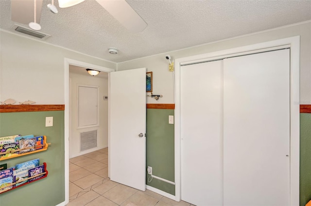 bedroom with light tile patterned floors, a closet, visible vents, and a textured ceiling