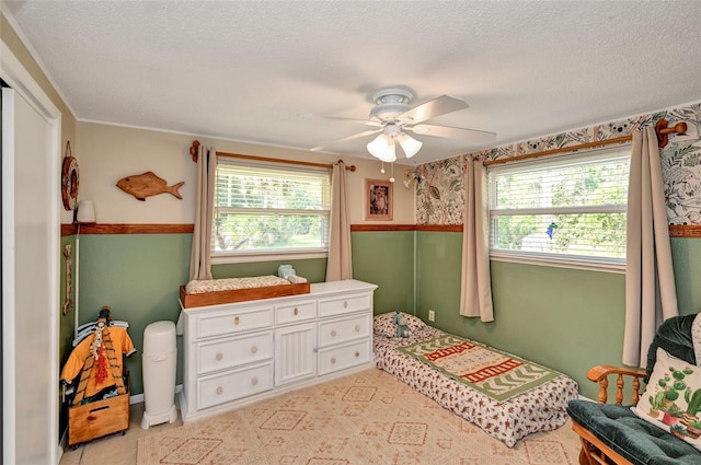 bedroom with a textured ceiling, multiple windows, and a ceiling fan