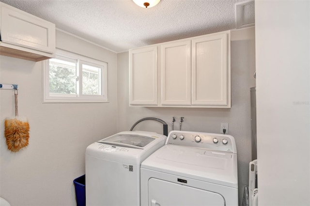 laundry area featuring cabinet space, a textured ceiling, and washing machine and clothes dryer