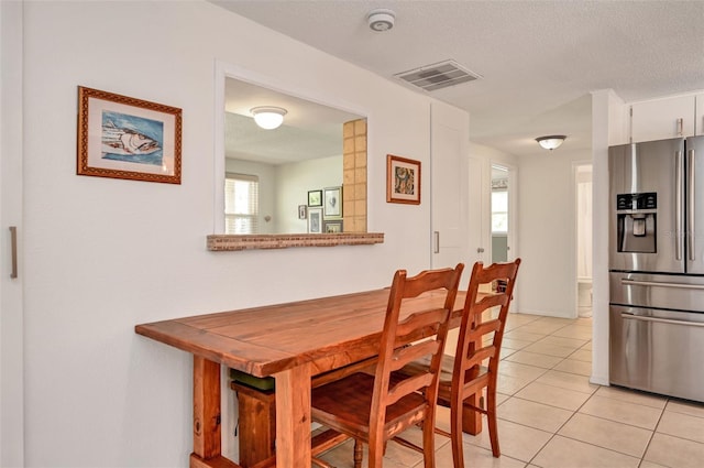 dining room with light tile patterned floors, visible vents, and a textured ceiling