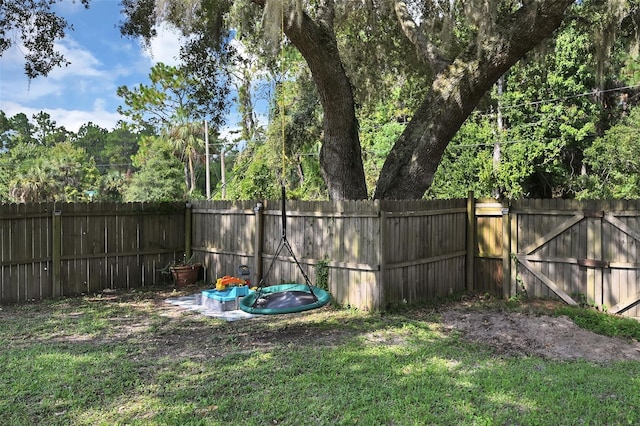 view of yard with a fenced backyard and a gate