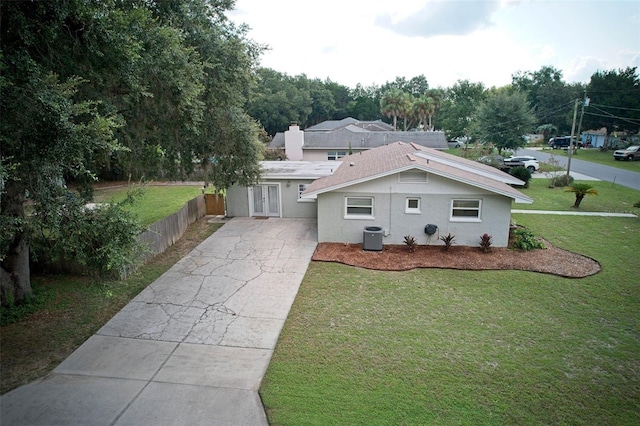 view of front of home featuring concrete driveway, a front lawn, central AC unit, and fence