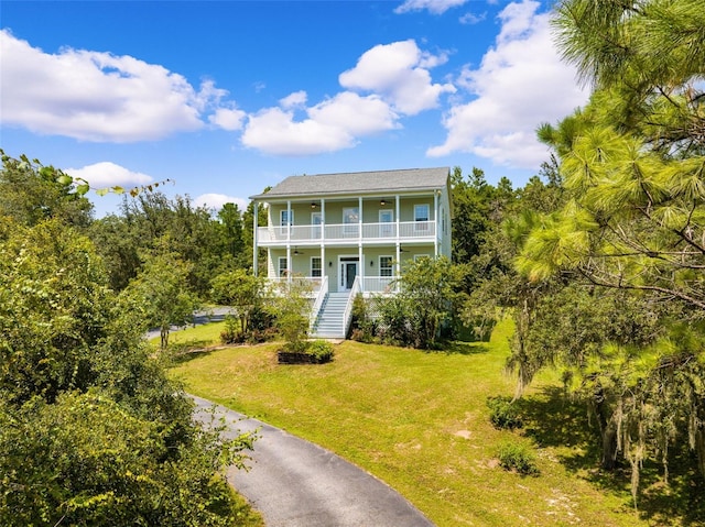 view of front facade featuring a balcony, a front yard, and covered porch