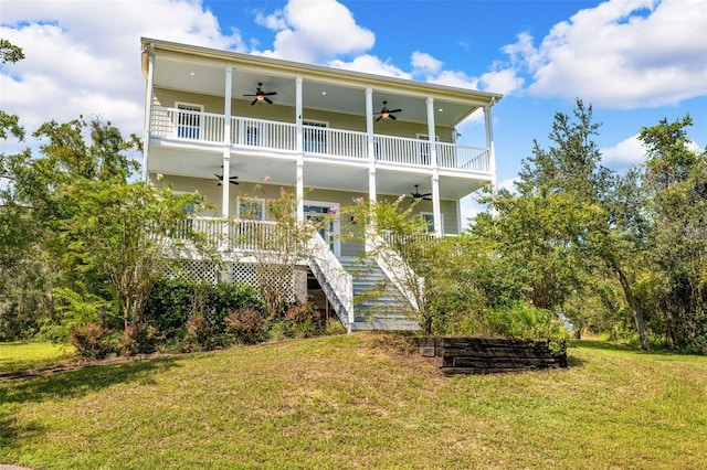 rear view of house featuring ceiling fan and a yard